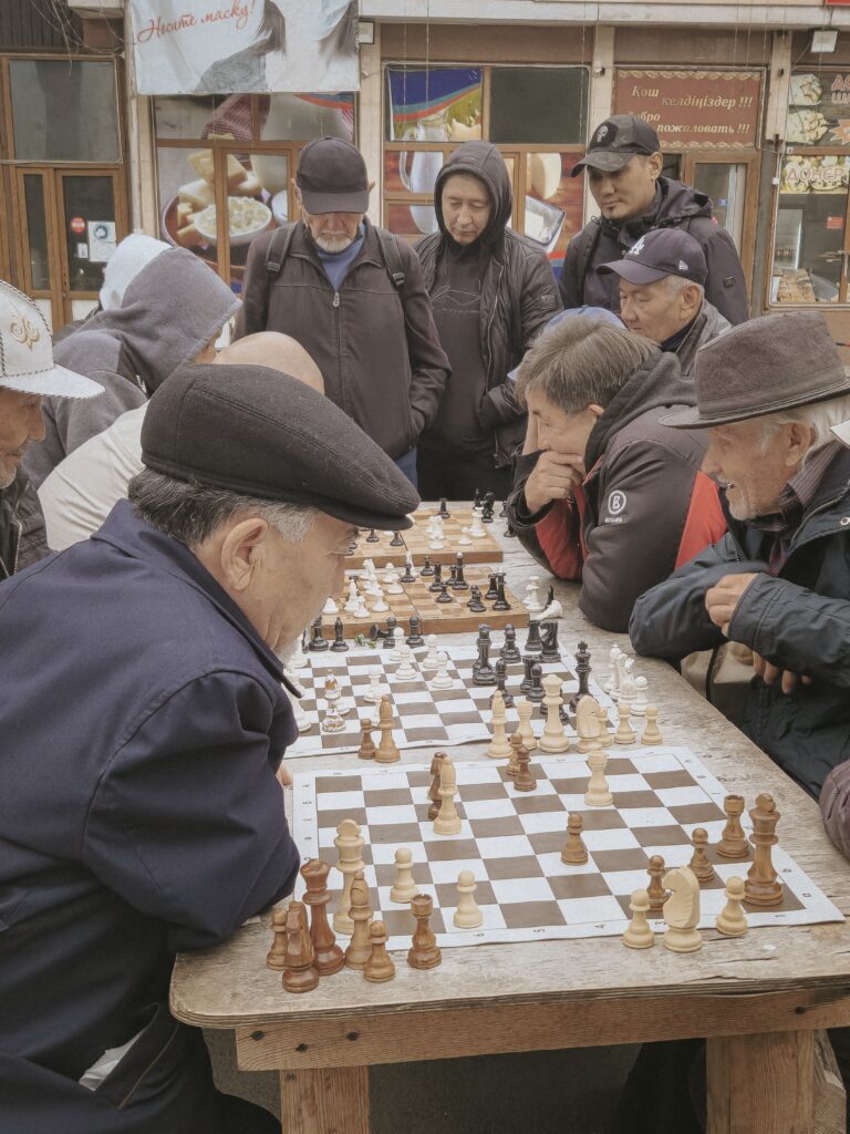 Foto de uma praça com idosos jogando xadrez.